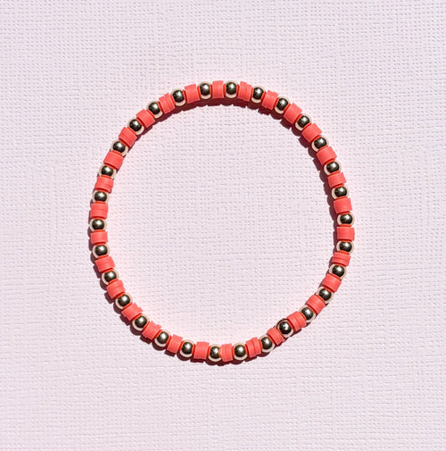 Bracelet with orange and gold beads on a light pink background
